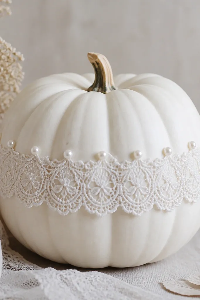 A white pumpkin wearing a white lace ring around the middle. Small pearl-like dots are spaced evenly along the lace at the top edge, like a collar.