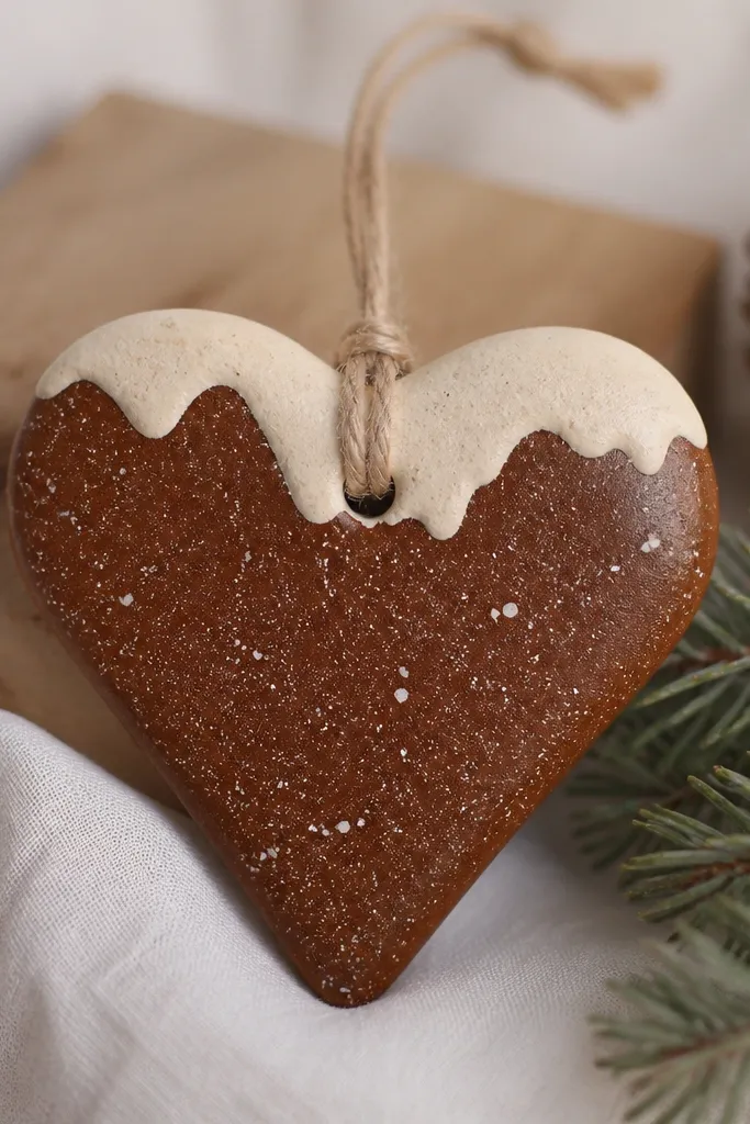 A heart-shaped salt dough ornament painted warm cocoa brown with tiny white speckles, with uneven cream "snowcaps" on the top edge and a thin clear gloss on the speckles.