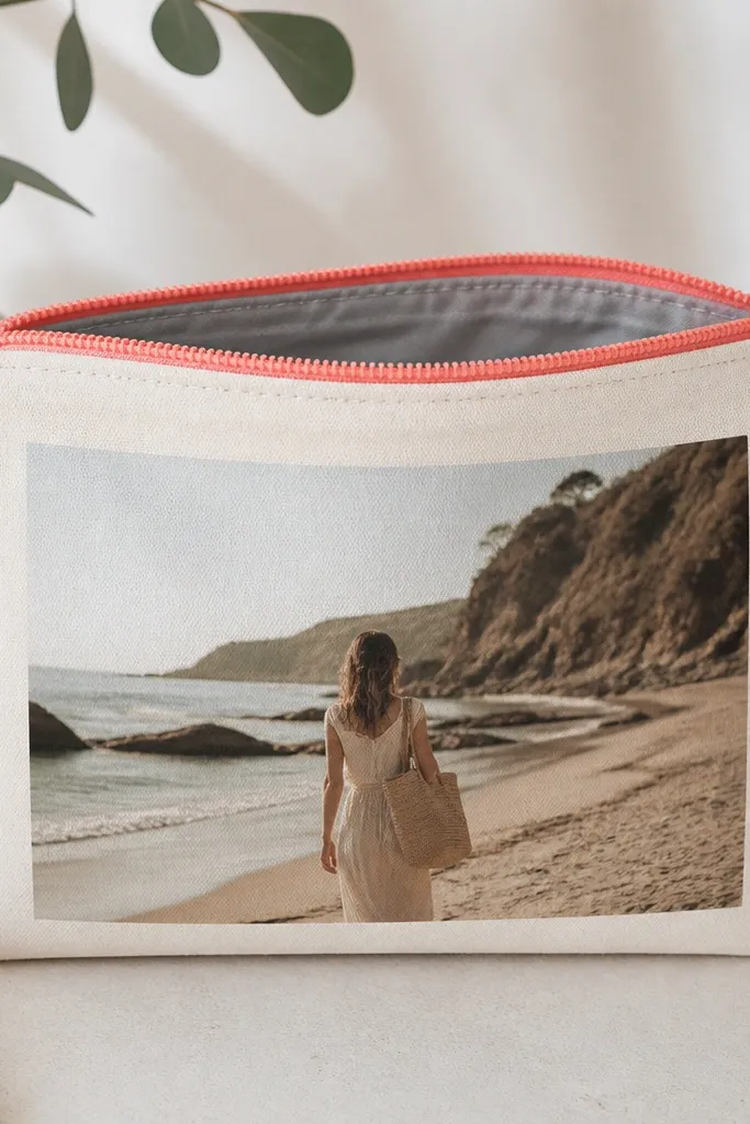 A medium zipper pouch showing a printed photo on the front panel. The photo is framed by solid cream fabric. The zipper is coral-pink, and the pouch has clean topstitching lines and a lined interior in soft gray cotton.
