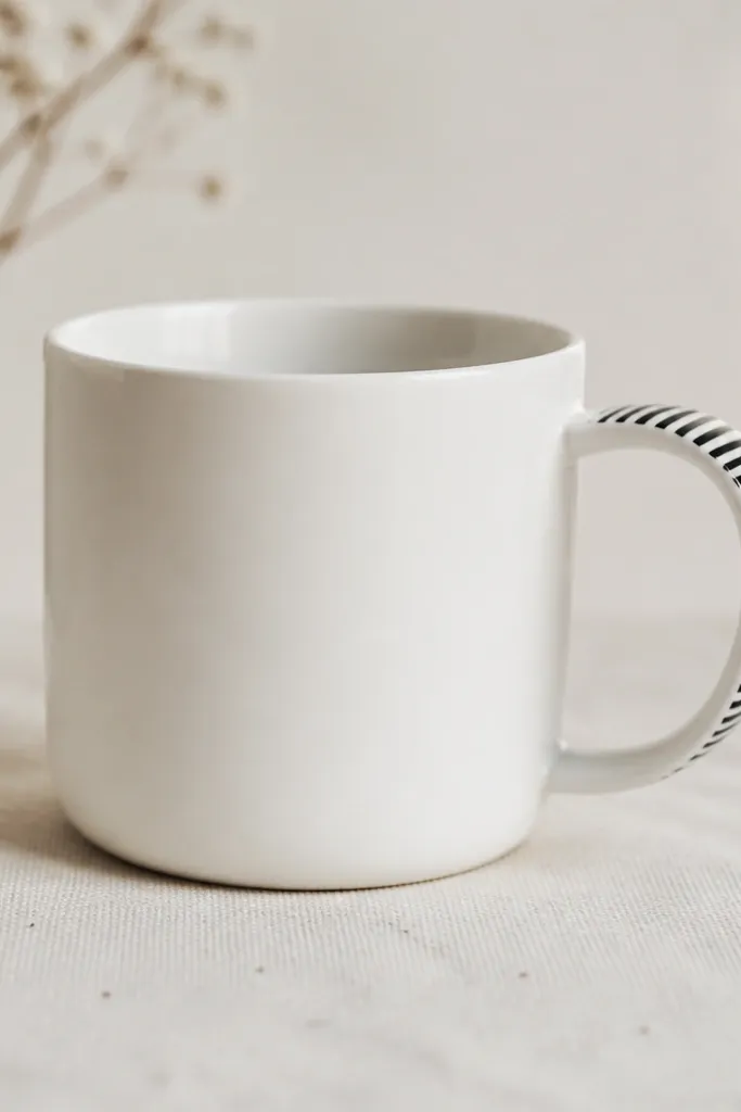 A white mug with a narrow wrap of monochrome stripes around the handle area only. The stripes are black and white, with the rest of the mug plain.