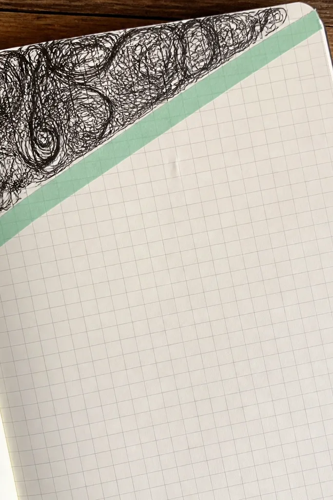 Journal page with a scribble-filled corner and a clean center grid for writing