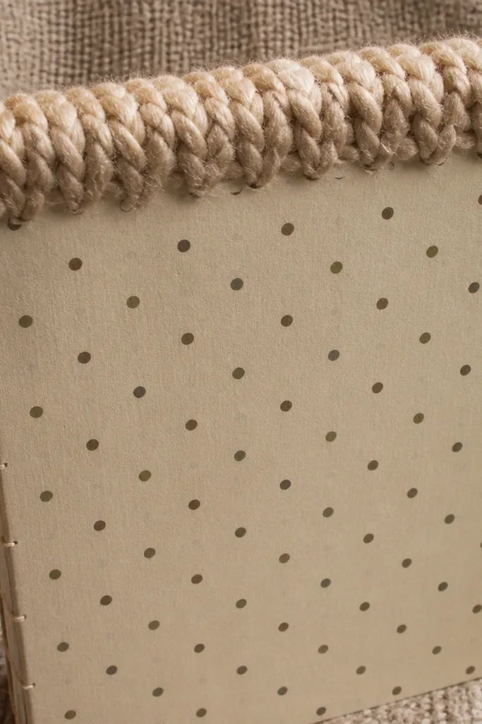 Cardboard cover with a yarn strip along the top edge and a simple centered title label