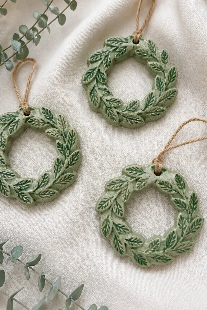 Small circular wreath ornaments with leaf texture. The base is light green, and the raised leaves have a darker green dry-brush highlight.