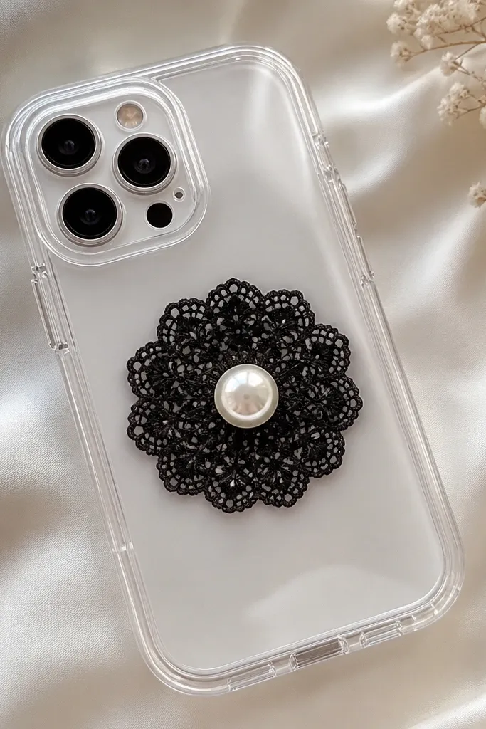 A clear TPU case with a small black lace circle placed in the center. A single faux pearl button sits on top, and everything is glossy and smooth.