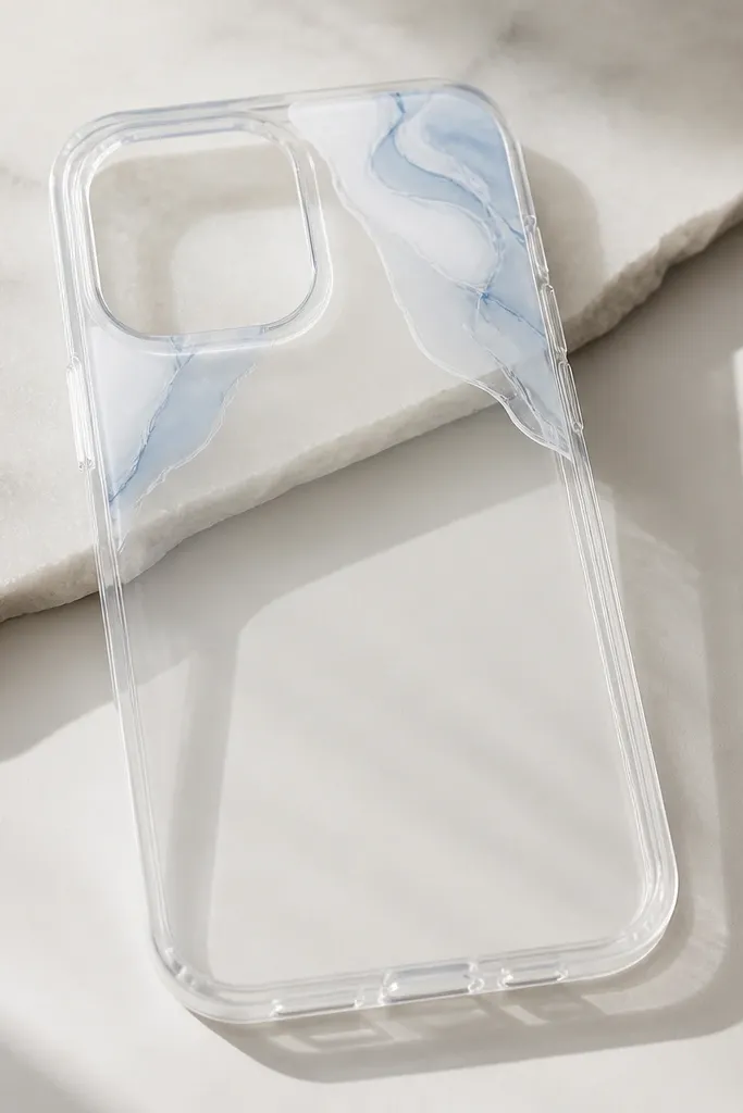A clear phone case with soft marble swirls only on the top corners, in white and pale blue, with crisp tape edges.