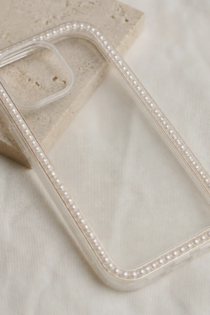 A clear or nude phone case with a pearl chain wrapped around the perimeter like jewelry; the pearls sit along the sides and the back is mostly clean.