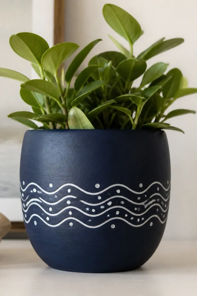A pot painted navy with white wave lines across the middle. Small white dots sit between the waves like bubbles.