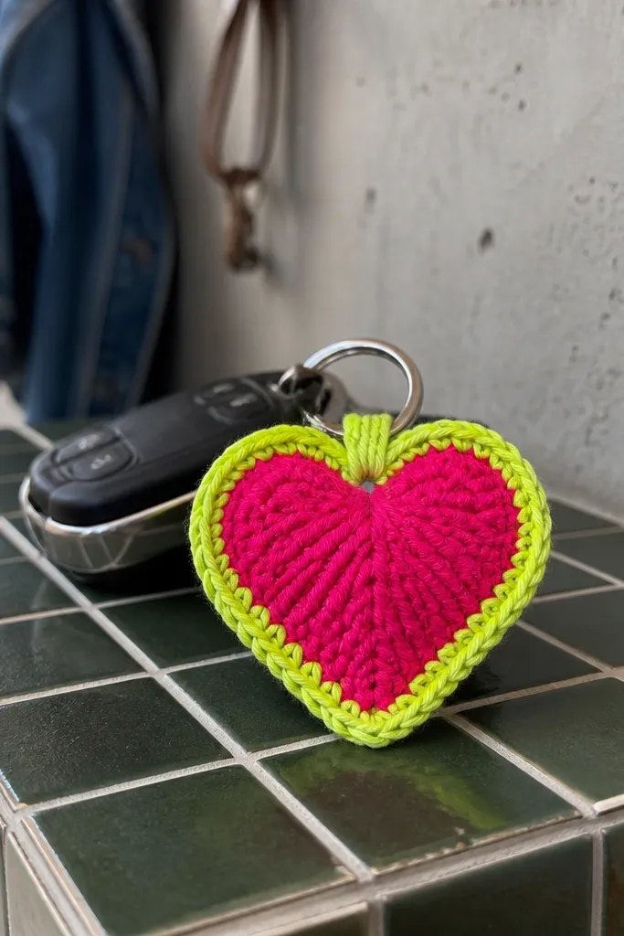 Neon pink and lime crochet heart keychain with a white single-crochet border
