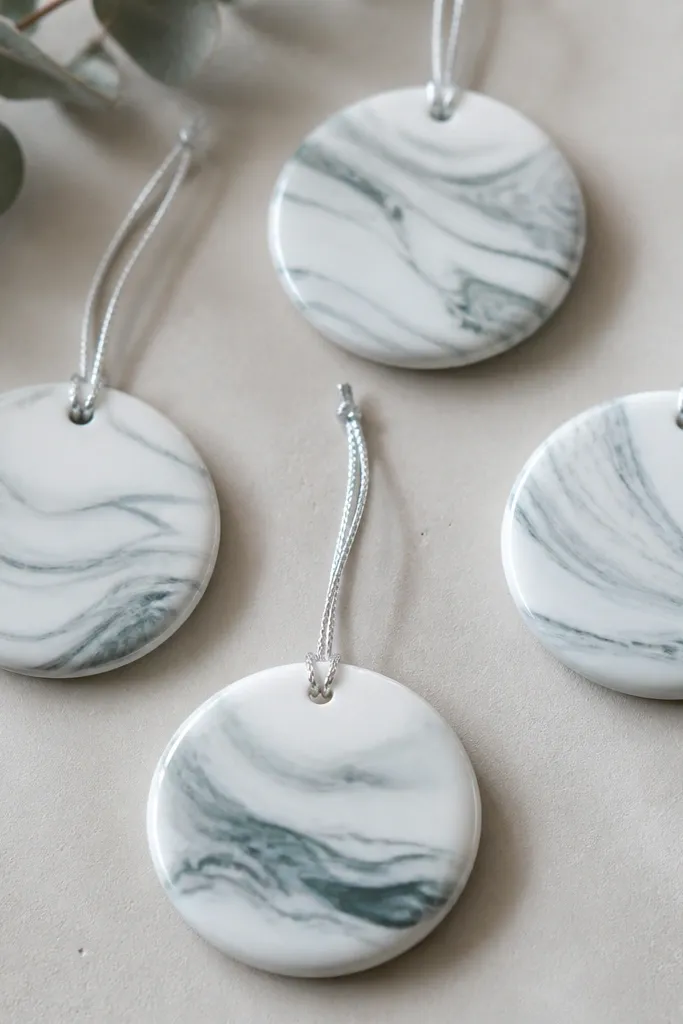 Round ornaments with a marbled pattern: white base with gray and soft teal swirls like stone, finished with a glossy satin coat. Each has a small drilled hole and a silver string loop.