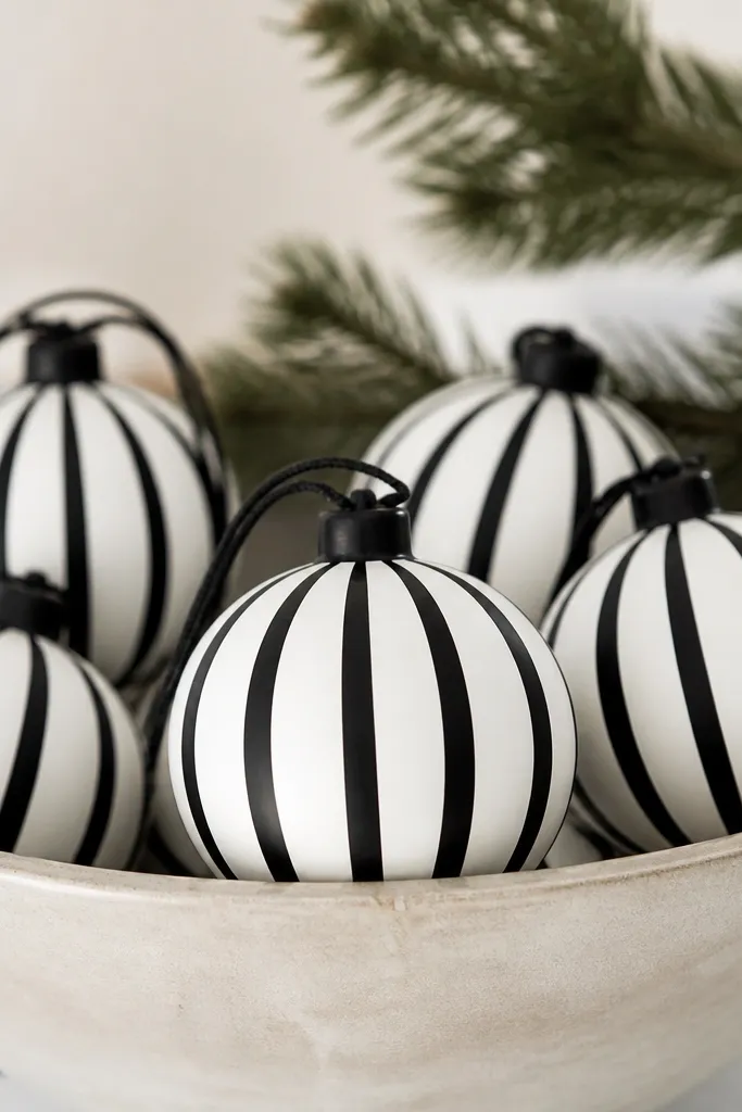 Round bauble ornaments painted white with bold black stripes wrapped vertically; the stripes are crisp and evenly spaced, with a black twine hanger and a satin finish.