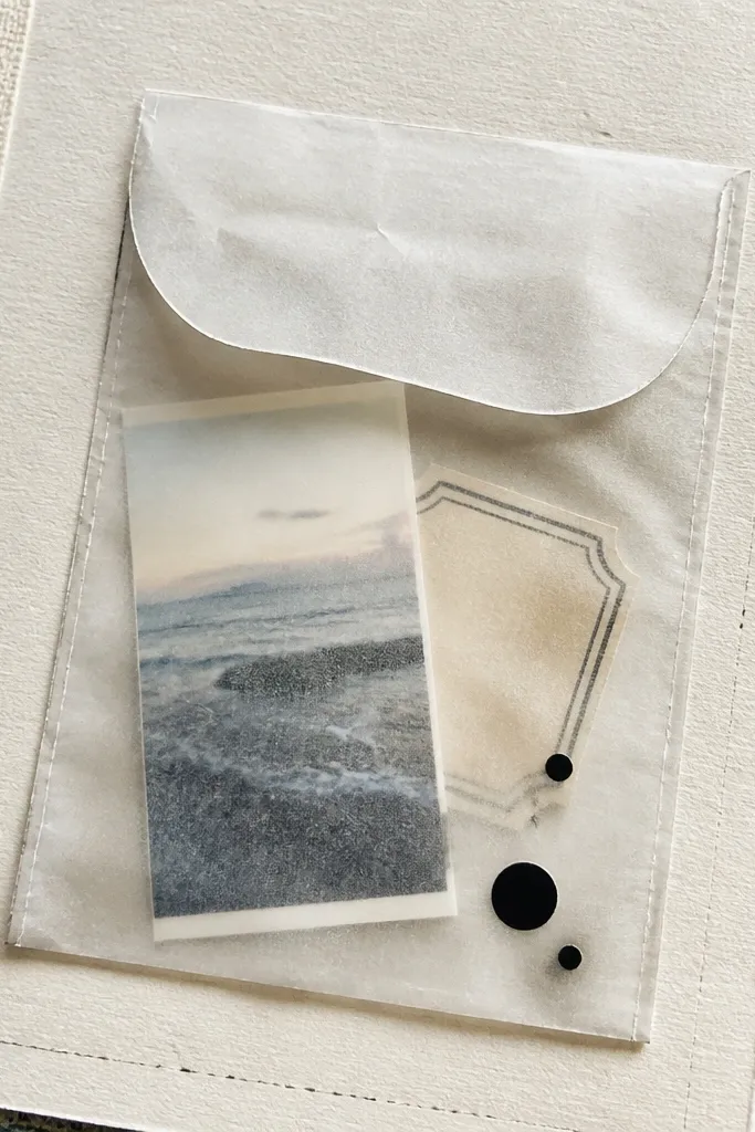 A vellum envelope on a scrapbook page with tiny slips inside