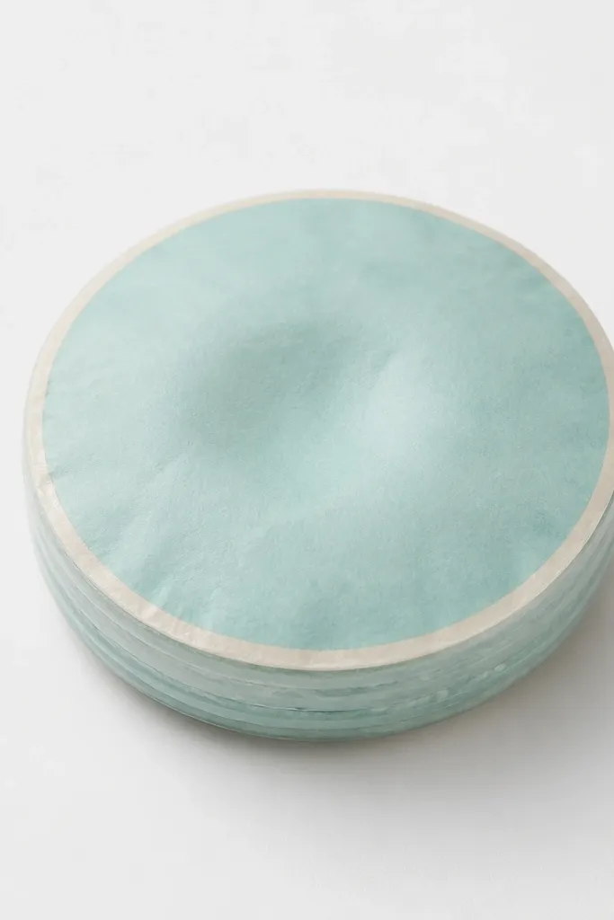 A small round coin-shaped paper squishy with a neat rolled edge. The front is pastel teal with a thin white border, and the center has a slight squish. The edge shows layered paper rings sealed under a clear matte top film. It's photographed close-up on a white background.