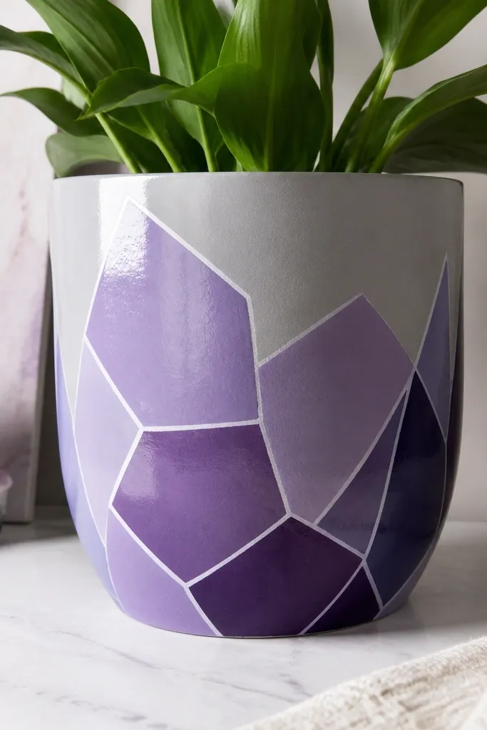 A light gray pot painted with faceted purple shapes like a geode, with thin white highlights along the edges; the finish is satin and glossy only where sealed.