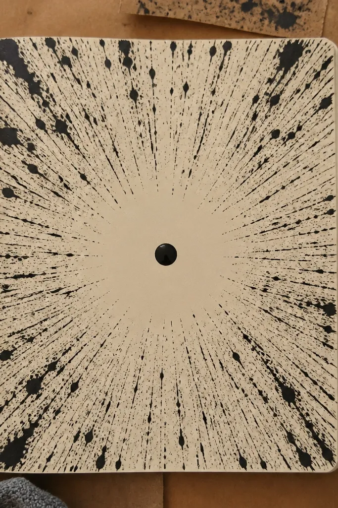 A sunburst made of splatter lines radiating from a center dot