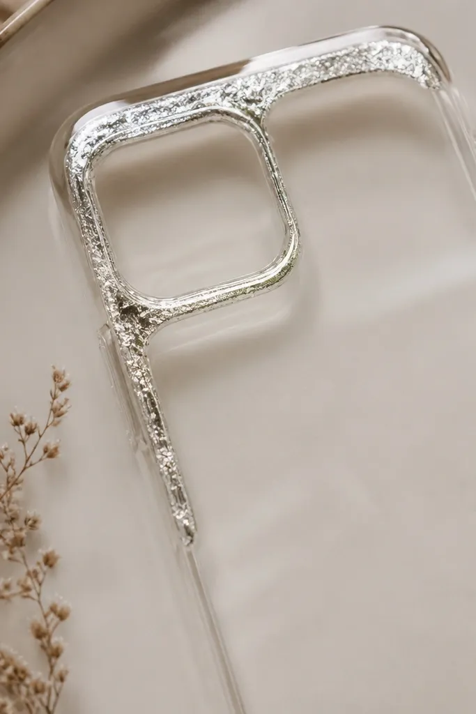 A clear case with a thin silver foil frame only in the top-left corner, like a partial picture frame, under glossy resin.