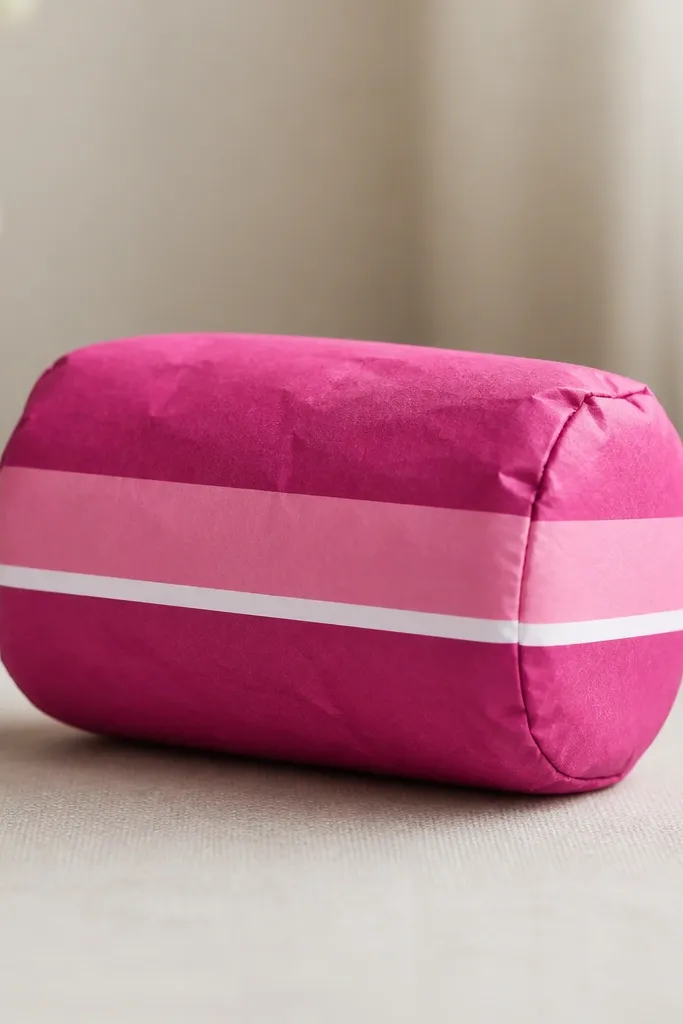 A magenta paper squishy shaped like a short roll. It has three horizontal stripes: deep magenta, lighter pink, and a thin white line between. The ends are rounded and the stripes align perfectly across the seam.