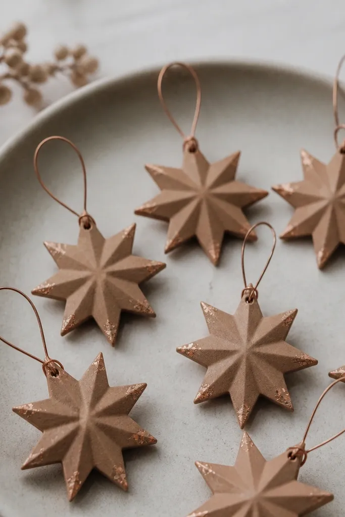 Small eight-point starburst ornaments with sharp corners, cinnamon-tan with tiny copper leaf flecks near the tips. Each piece hangs on a thin copper wire loop.