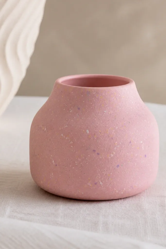 A matte light pink mini pot covered in scattered specks and tiny dashes in pastel colors: white, pale yellow, lavender, and mint. The specks vary in size slightly, like sprinkles, with a satin clear finish.