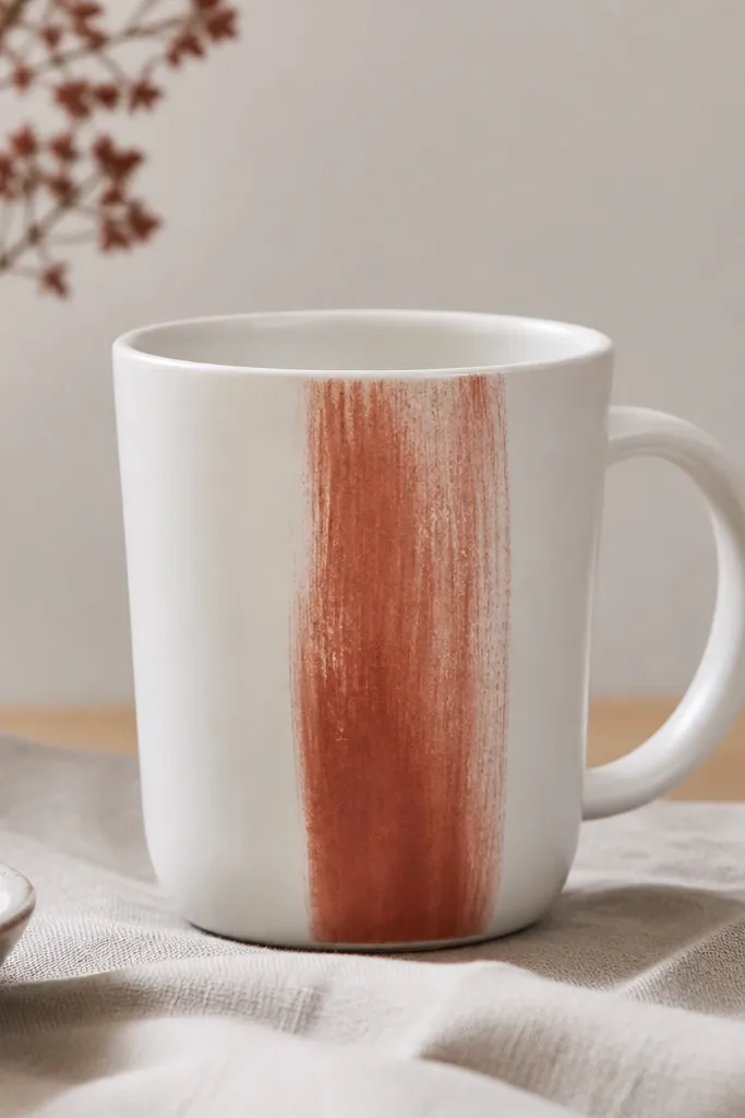 A white mug with a terracotta drybrushed vertical stripe near the front, with visible brush texture and soft edges.